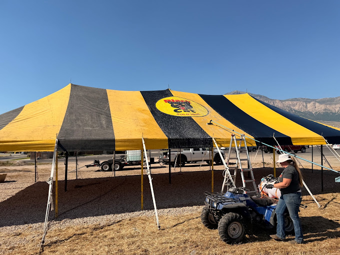 Large black and yellow event canopy being professionally cleaned beneath Northern Utah mountains